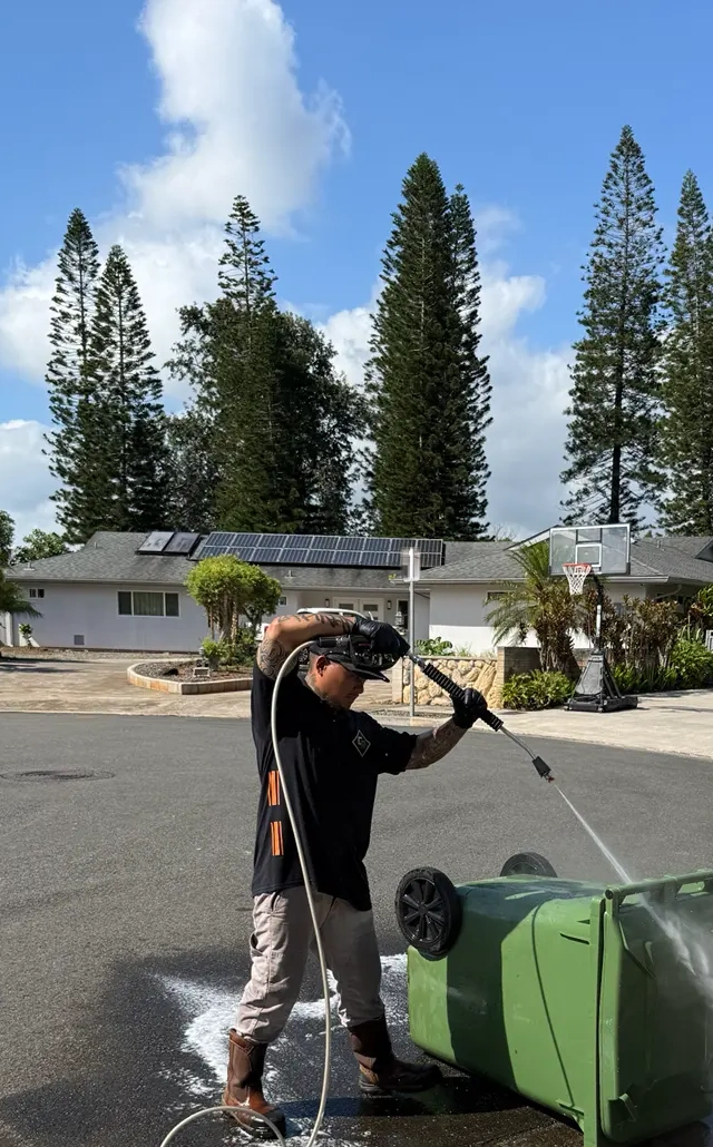 Clean Route Systems technician rinsing and sanitizing a residential bin on an Oʻahu street
